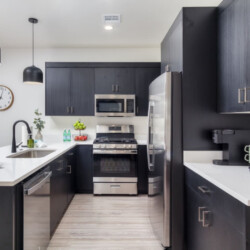 Modern kitchen with dark navy cabinets, white countertops, and a large island with stainless appliances.