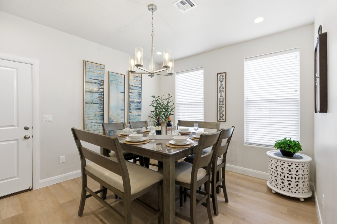 Dining room with a dark wood table for eight, beige upholstered chairs, and a chandelier overhead.