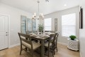 Dining room with a dark wood table for eight, beige upholstered chairs, and a chandelier overhead.