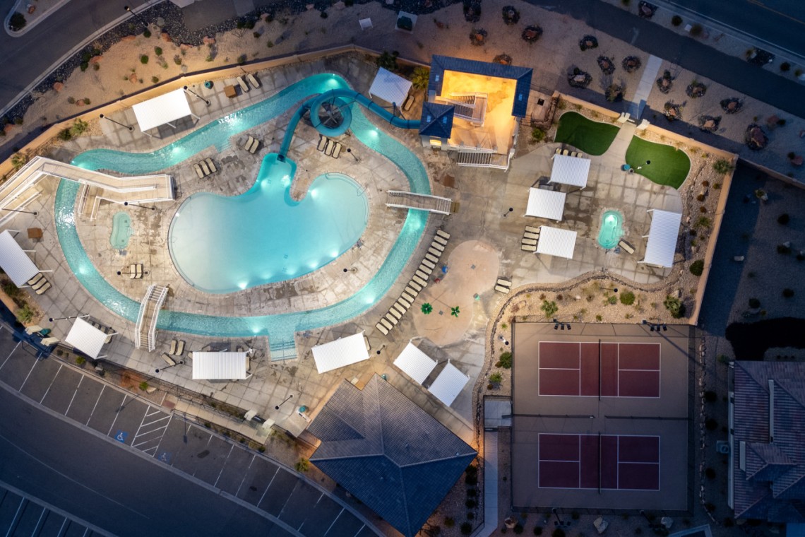 Aerial view of a resort pool area with a winding turquoise lazy river, multiple water slides, and surrounding lounge chairs and cabanas at dusk.