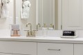 Hotel bathroom vanity with brushed-nickel faucet, clear soap dispenser, and a makeup-towel rack on the counter, plus a small card encouraging use of makeup towels and a black towel labeled 'Makeup' in a dotted tray.