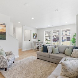 Bright open living room with a beige sectional, fluffy rug, and large windows filling the space with daylight.
