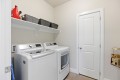 Laundry room with a white washer and dryer under a shelf holding wicker baskets