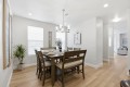 Dining room with a dark wood table set for six, a chandelier overhead, and a plant near the window.