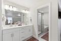 Double-sink bathroom vanity with white cabinets, large mirror, and brushed-nickel fixtures in a bright, modern master bathroom.