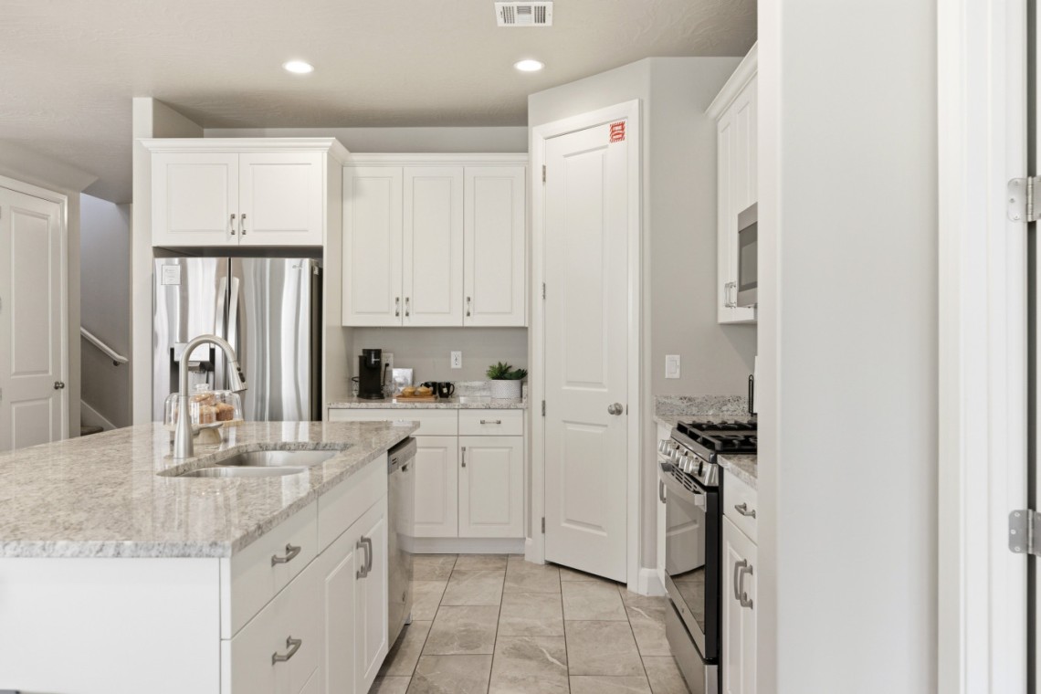 White kitchen with granite island, double sink, and stainless steel refrigerator