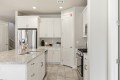 White kitchen with granite island, double sink, and stainless steel refrigerator