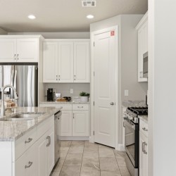 White kitchen with granite island, double sink, and stainless steel refrigerator