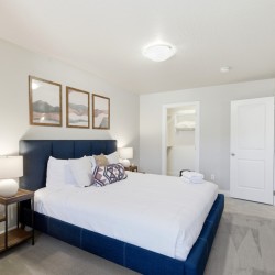 Hotel-style bedroom with a blue upholstered king bed, white bedding, and matching nightstands with lamps on each side.