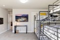 Dorm room with gray metal bunk beds on the right, a desk under a cityscape wall art, and an open doorway to a hallway.