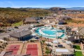 Aerial view of a desert resort-like community with a large central swimming pool, water slide, lounge chairs, and surrounding houses.
