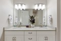 Double-sink bathroom vanity with a potted plant center, mirrors, and white towels on rings flanking the sinks.