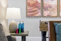 Living room scene with a ceramic lamp on a side table, two water bottles, and a Nintendo Switch with red and green Joy-Cons; a foosball table in the background.