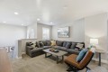 Cozy living room with a large gray sectional, rectangular coffee table, and a brown leather lounge chair. A lamp and framed art decorate the space.