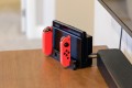 Nintendo Switch console in its dock with red Joy-Con controllers attached on a wooden table.