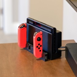 Nintendo Switch console in its dock with red Joy-Con controllers attached on a wooden table.