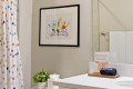 Framed colorful animal illustration on a gray bathroom wall, with a polka-dot shower curtain on the left and a white countertop with decor on the right.