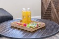 Wooden tray on a round metal table holding two Sparkling ICE bottles and Skittles candy bars on an outdoor patio table.