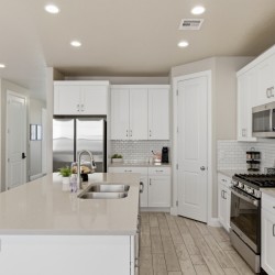 Bright white kitchen with an island, double sink, and stainless steel fridge and appliances.