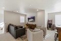 Cozy basement living area with a dark gray sectional, two beige chairs, and a mounted TV above a wooden cabinet.