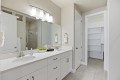 Bright modern bathroom with a double vanity, white cabinetry, and a large illuminated mirror above two sinks.