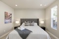 Bedroom with a gray tufted headboard, two nightstands with lamps, and a window with blinds on the right.
