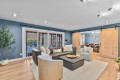 Spacious living room with blue walls, a black leather sectional, two woven chairs, and a beige rug, plus sliding barn doors to a dining area.