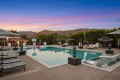 Luxurious outdoor pool area at dusk with striped lounge chairs, umbrellas, and mountain backdrop.