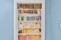 White built-in bookshelf inside a doorway, five shelves of colorful books against blue walls.
