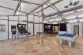 Indoor games room with pool table, foosball, arcade basketball game, and a seating area with a TV in the back corner.