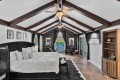 Luxurious loft bedroom with a black tufted bed, white bedding, and dark wood beam ceiling.
