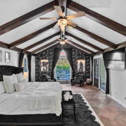 Luxurious loft bedroom with a black tufted bed, white bedding, and dark wood beam ceiling.