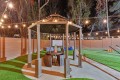 Nighttime backyard gazebo with string lights, a round table, wicker stools, and a Jenga tower on the table.