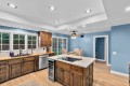 Bright kitchen with blue walls, dark wood cabinets, a central island with a cooktop, and a dining area beyond.