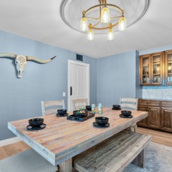 Blue-dk dining room with a rustic wooden table, bench seating, and a longhorn skull wall decor above one wall
