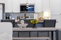 Black wire fruit bowl with lemons and limes on a kitchen island in a modern white-kitchen setting.