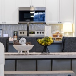 Black wire fruit bowl with lemons and limes on a kitchen island in a modern white-kitchen setting.