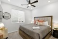 Bedroom with a wooden bed, gray bedding, and multiple pillows, plus two nightstand lamps.