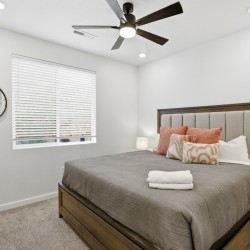 Bedroom with a wooden bed, gray bedding, and multiple pillows, plus two nightstand lamps.