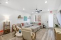 Cozy living room with a light gray sectional sofa, two beige armchairs, round ottoman, and a neutral rug.