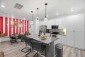 Modern kitchen and dining area with white cabinets, gray island, stainless appliances, and a bold red-and-white striped accent wall