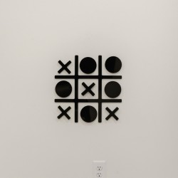 Decorative wall art of a tic-tac-toe grid with black X and O shapes on a white wall.