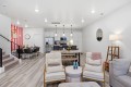 Open-concept living space with a bright kitchen, white cabinets, stainless-steel appliances, and pendant lights over an island.