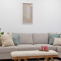 Beige sectional sofa with multiple decorative pillows in a bright living room; a wooden coffee table with a tray of pink drinks sits in front.