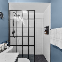 Blue bathroom with a black-framed glass-paned shower door, white subway tiles, and towels on dark blue walls.